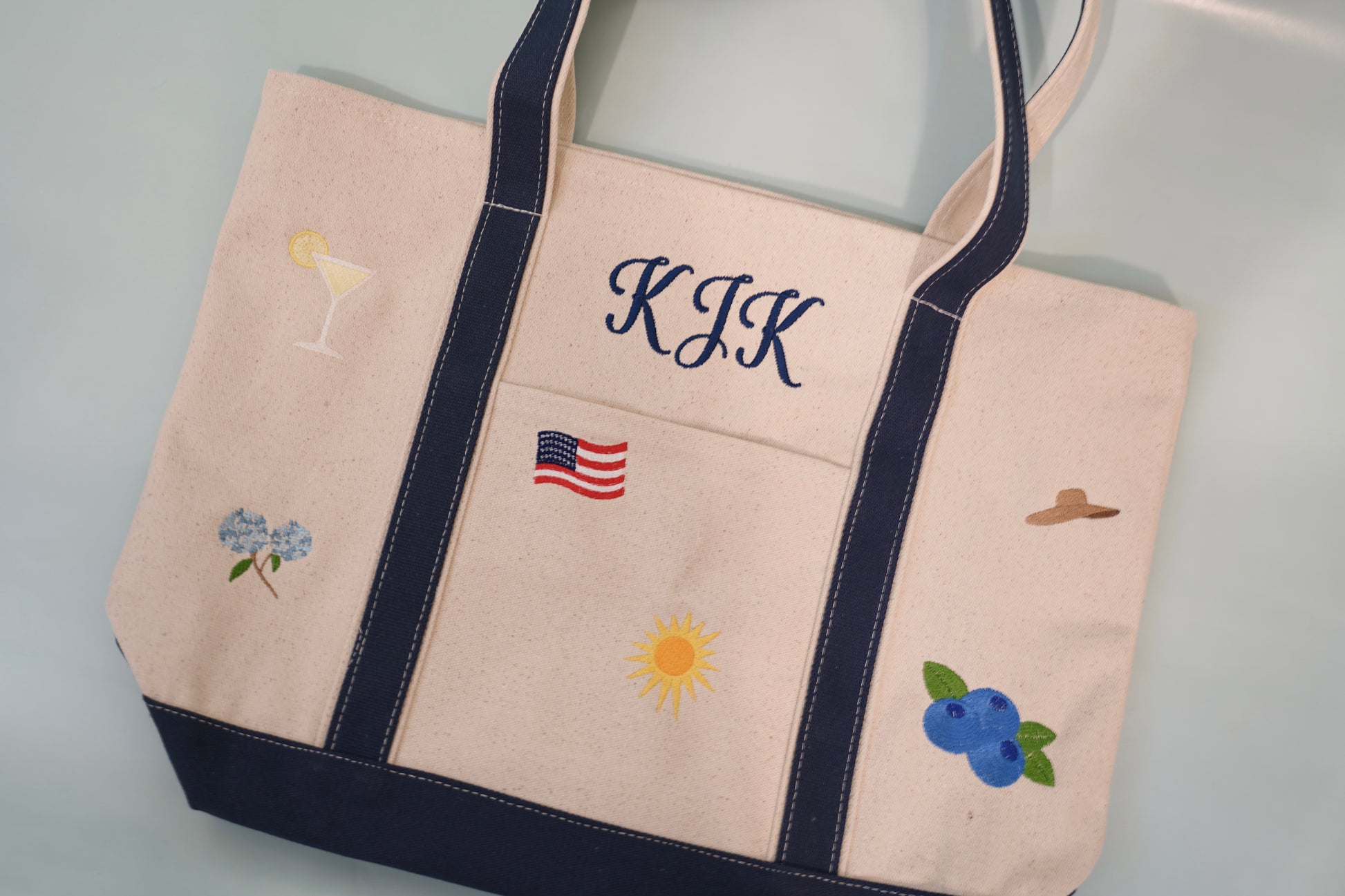 Front view of custom embroidered canvas tote bag featuring monogram and Americana summer icons.”